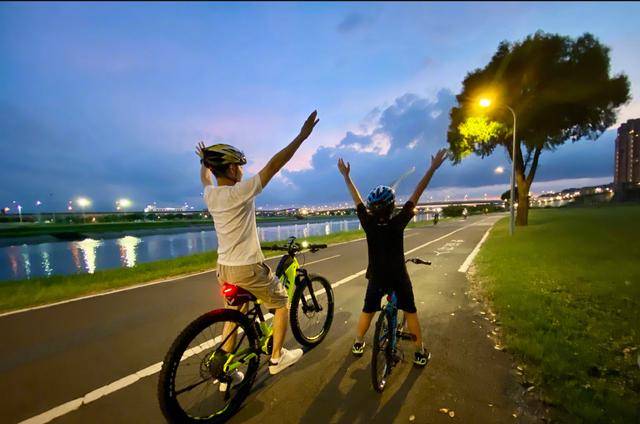 远处夕阳西下,趁着路人行人比较少,二人坐在自行车上,kimi看起来相比