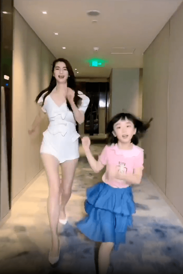洪欣6岁的女儿张晞彤身穿粉色上衣搭配蓝色裙子,在妈妈前面开心的蹦蹦