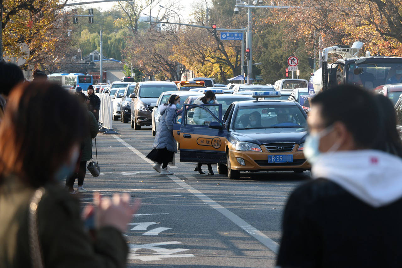 一辆出租车在故宫北门外的道路中央直接停车接乘客,后方车辆只能排队
