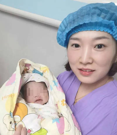 图为:助产士宋娜抱着亲手接生的婴儿