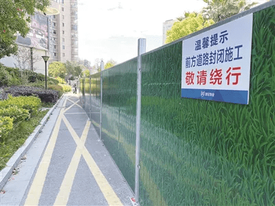 挡板上张贴的"温馨提示"醒目告知:前方道路封闭施工,敬请绕行.