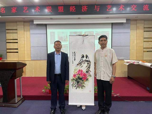 在活动现场,中名联签约艺术名家朱立强(右)为房山区失学儿童献爱心