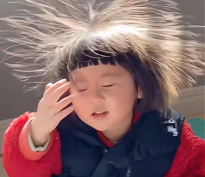 小女孩穿上衣服以后自己在床铺上玩耍,妈妈正在厨房里做饭.