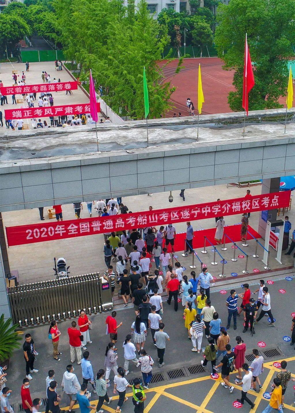 在遂宁中学介福校区考点外,考生们佩戴口罩,接受体温检测后进入