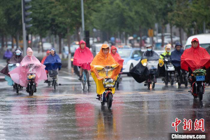 市民穿雨衣骑车冒雨出行. 韦亮 摄