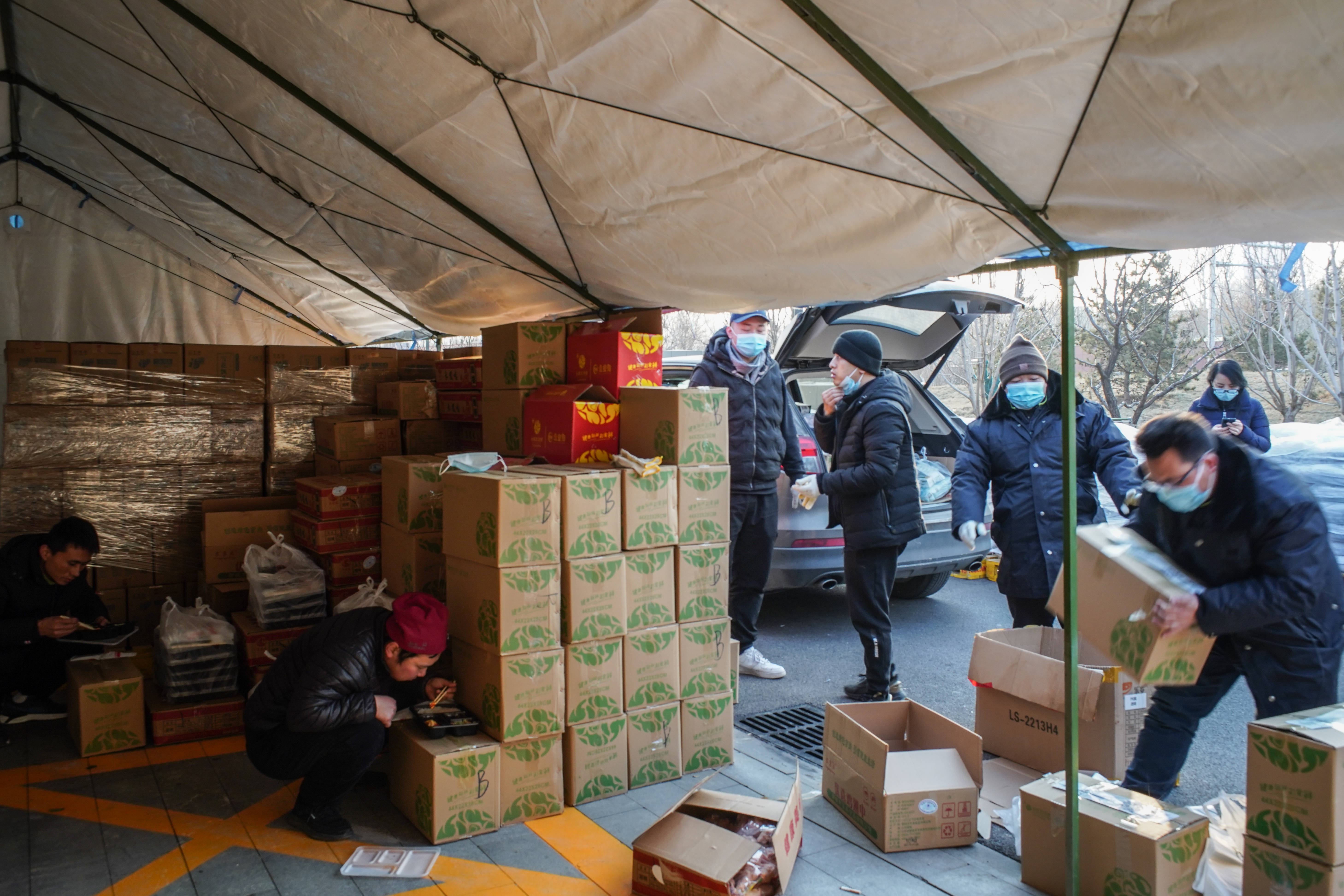 1月20日下午,工作人员在物资供应网点分拣商品装车,有的工作人员(左一