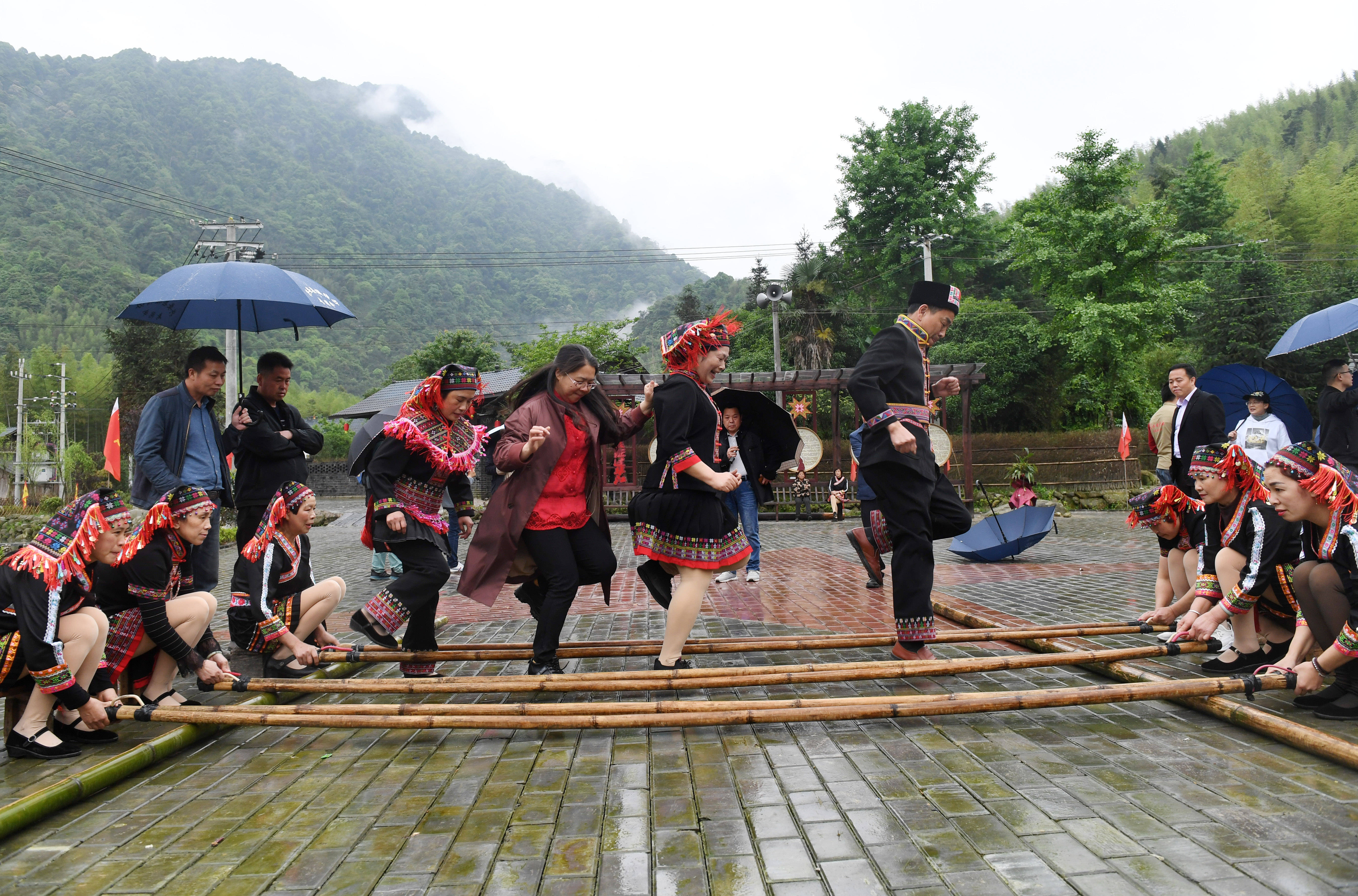 在广西兴安县华江瑶族乡龙塘寨,当地村民和游客一起跳竹竿舞(4月28日