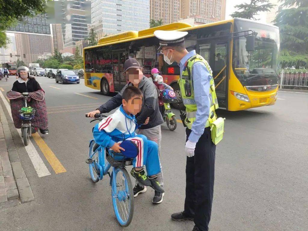 5月28日7时40分,雁宁路小学门前家长车筐载孩子上学.