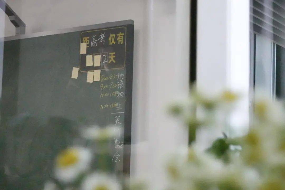 倒计时牌子上标注着"距离高考仅2天";教室窗台外,向日葵,小雏菊开得