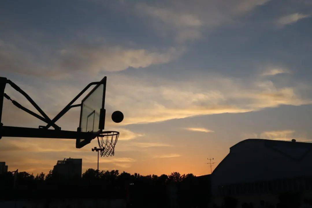 日落拉开晚霞的帷幕 昏黄的光晕极致温柔 篮球恰与夕阳相对 只