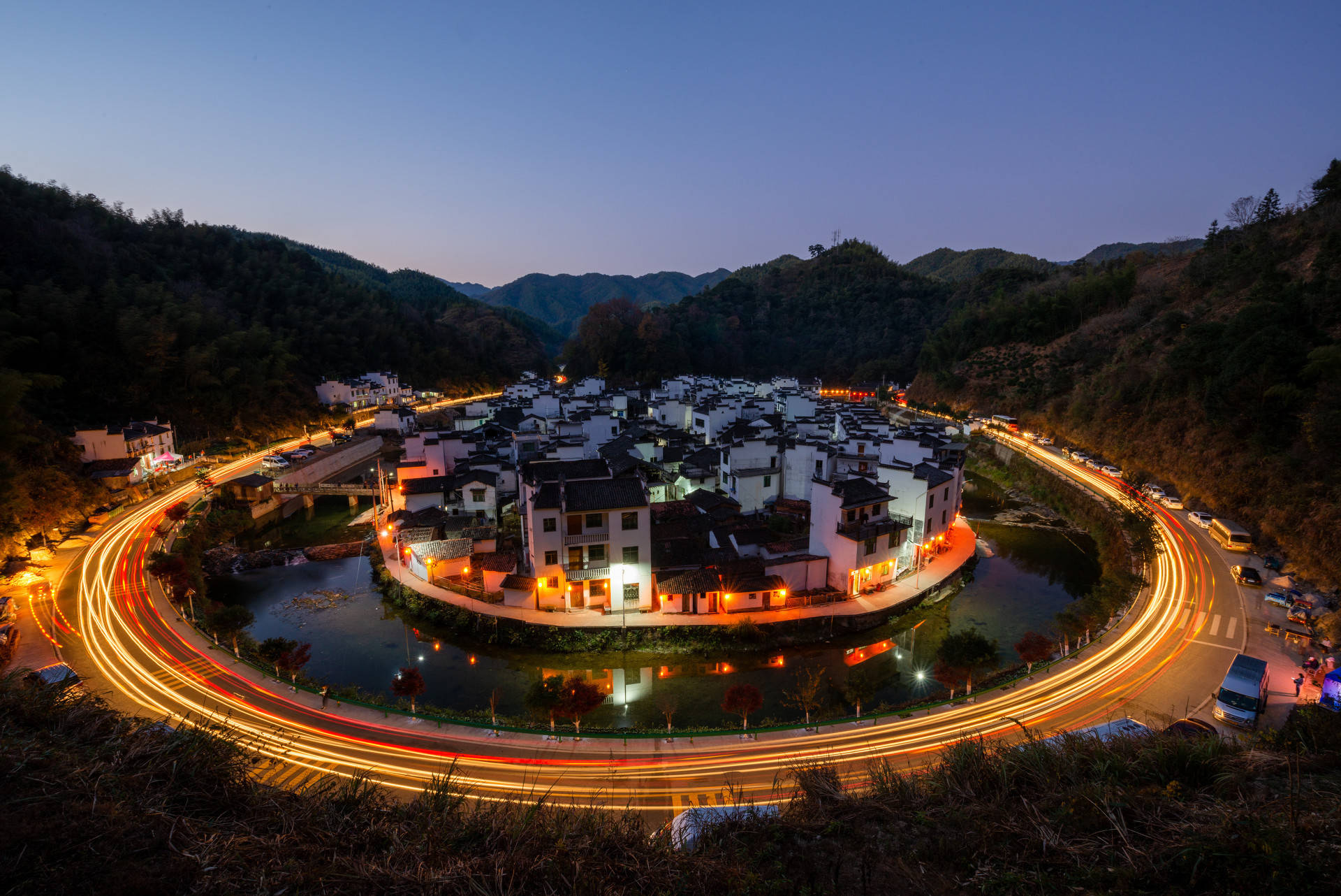 一个巨大的圆形八卦阴阳鱼镶嵌在青山绿水间,村中白墙青瓦的徽派建筑