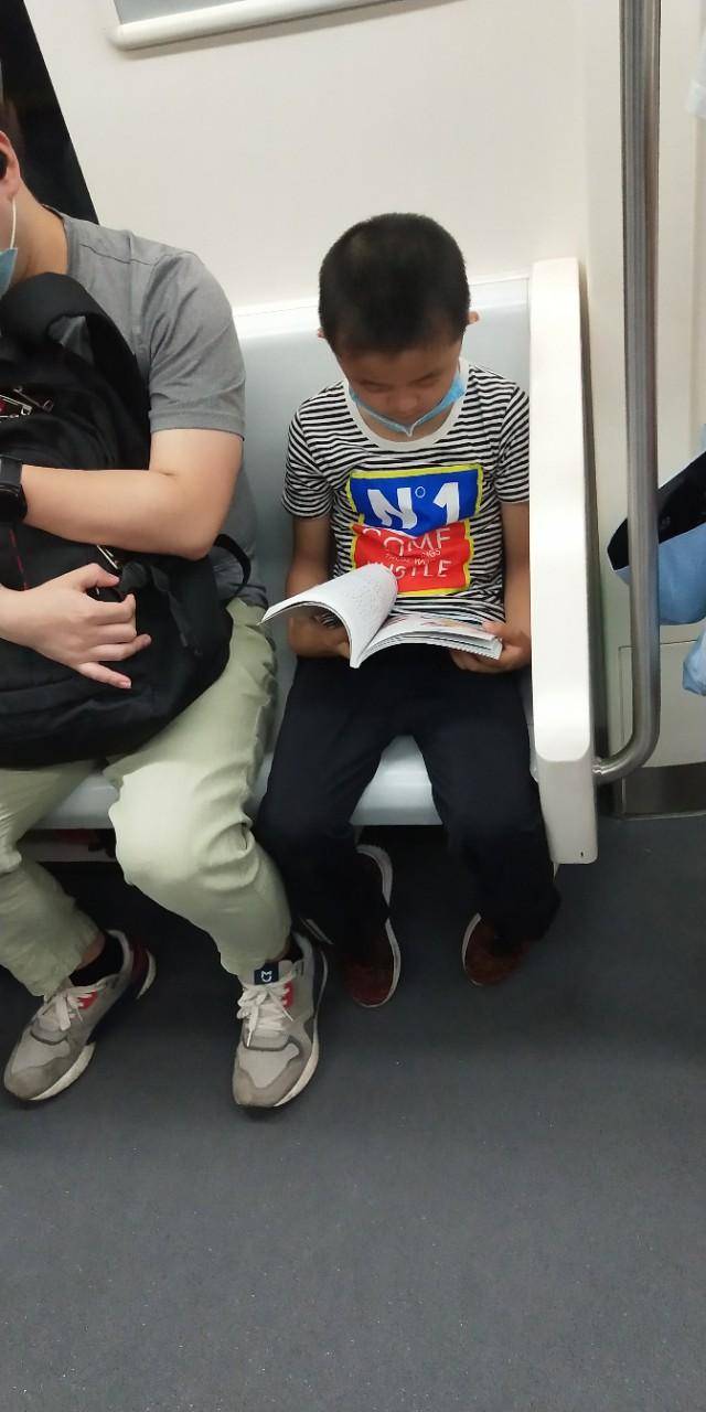 地铁里大家都在低头看手机,这个小孩的动作亮了.