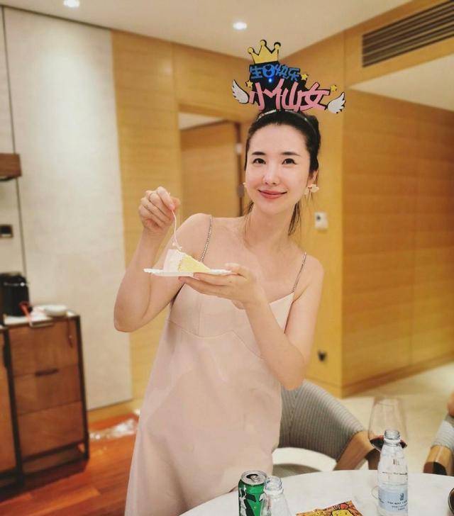 在她生日当天,穿着一件粉色的真丝吊带裙,看样子是和家人聚餐,手里捧