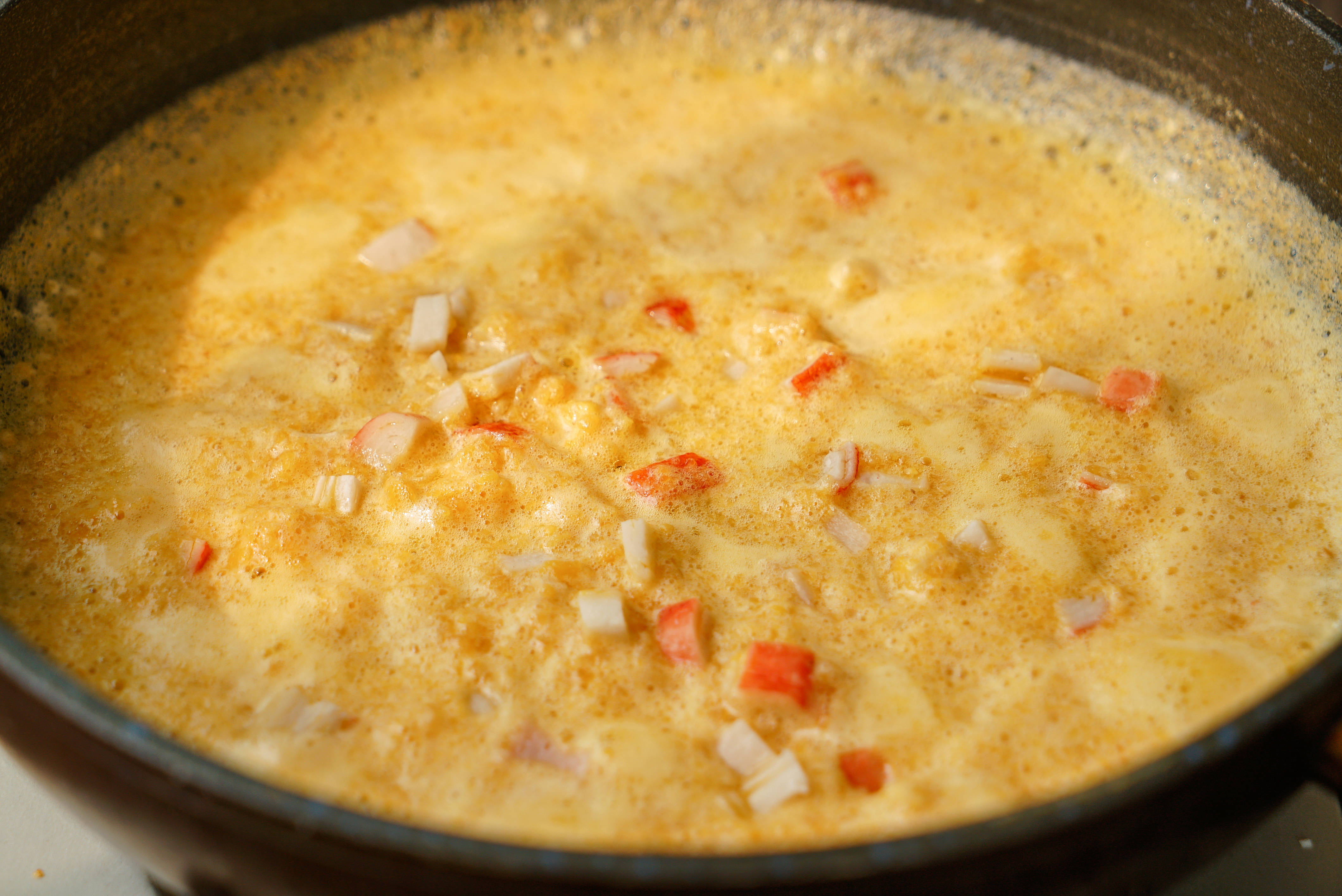 步骤6紧接着下入蟹棒碎,稍微的翻炒一下,下入沥干水的豆腐,下入豆腐