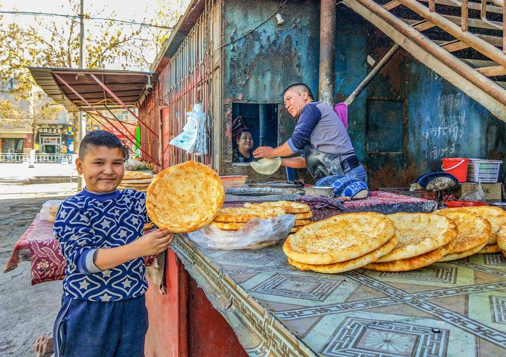 维吾尔族一家在街头卖烤囊奔小康,脸上洋溢着幸福的笑容.刘琳/摄