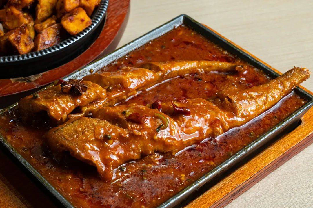 卖相很好浓郁的酱汁淋在了鱼肉之上两条明太鱼整齐地摆放在铁板上几乎