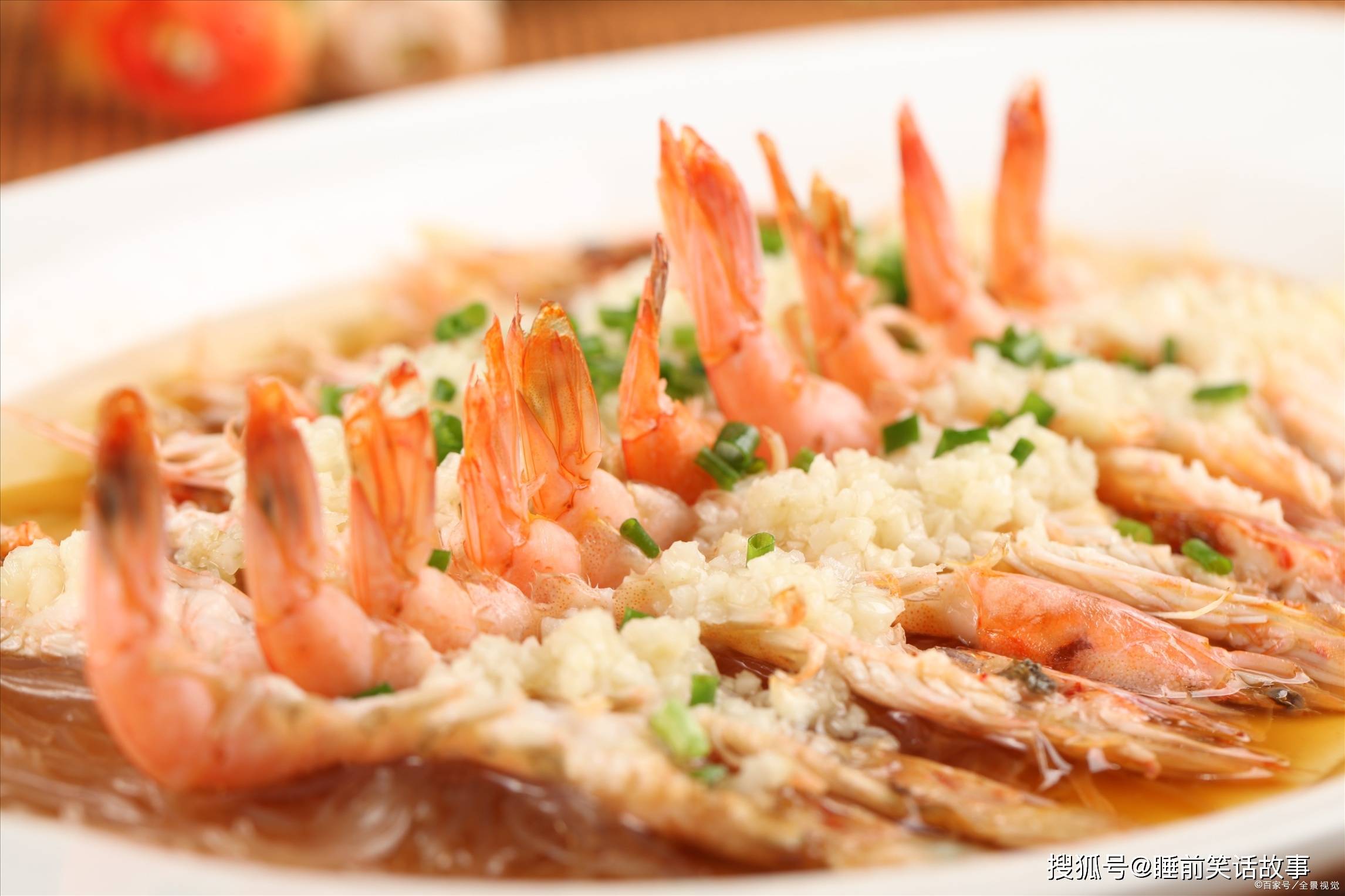 4,将泡好的粉丝摆在盘子里,把处理好的虾放在上面,蒜蓉铺在虾背上