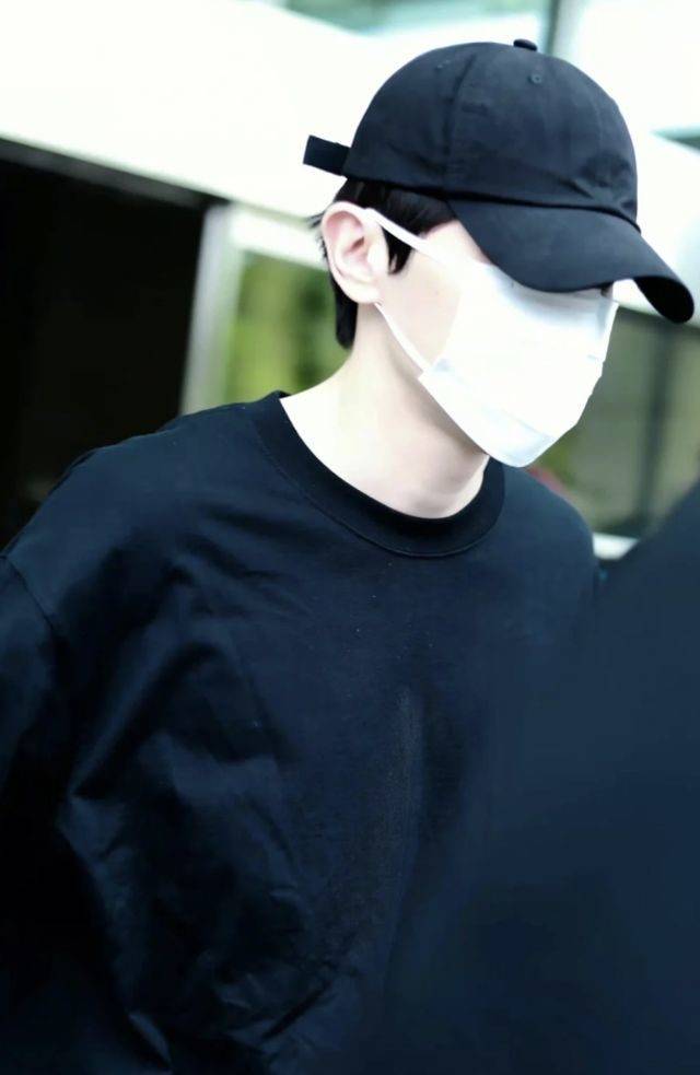 穿着一身黑色装束,带着黑色棒球帽和白色口罩的邓伦本人,手里拿着手机