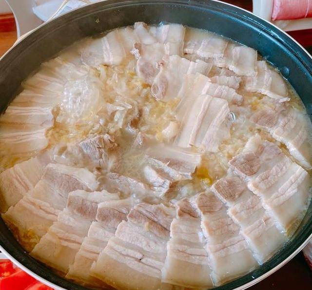 【步骤4】将酸菜铺在砂锅的锅底,放入盐,十三香,糖,八角,葱,姜,蒜