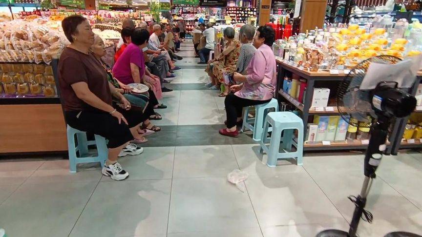因天气太热,大爷大妈组团到超市乘凉,坐过道两侧如"检阅"顾客