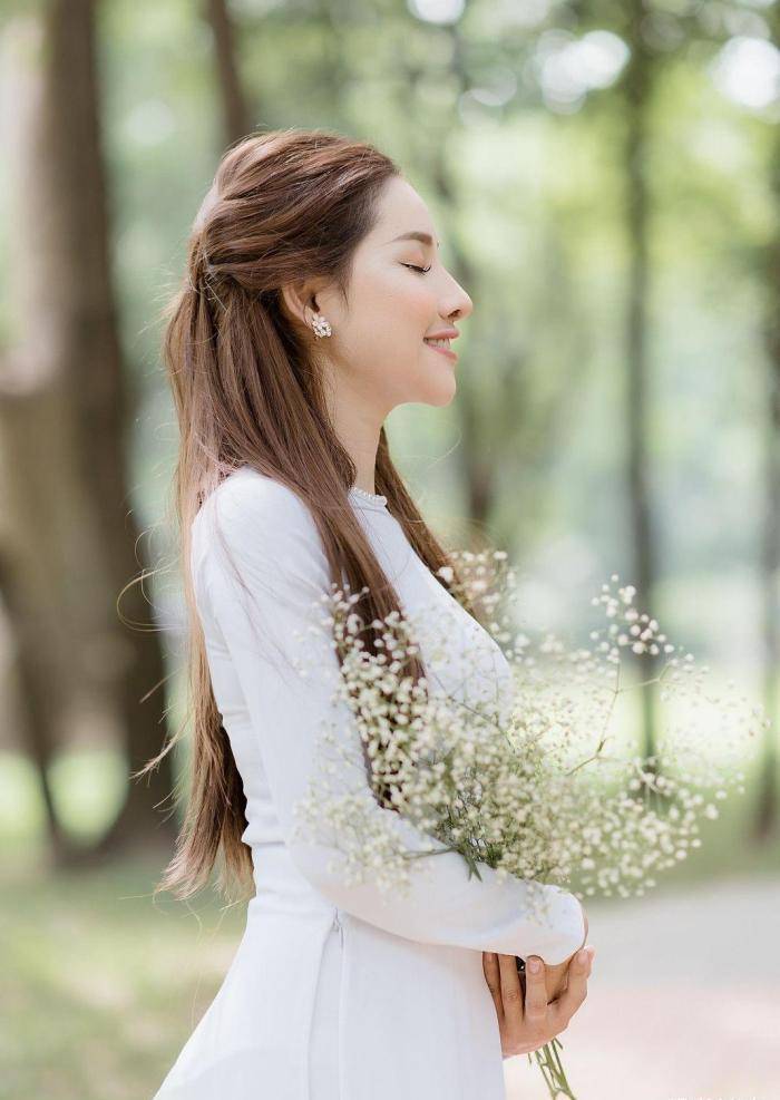 手捧鲜花,身穿白色奥黛,气质温婉,笑容阳光的国外姑娘真美