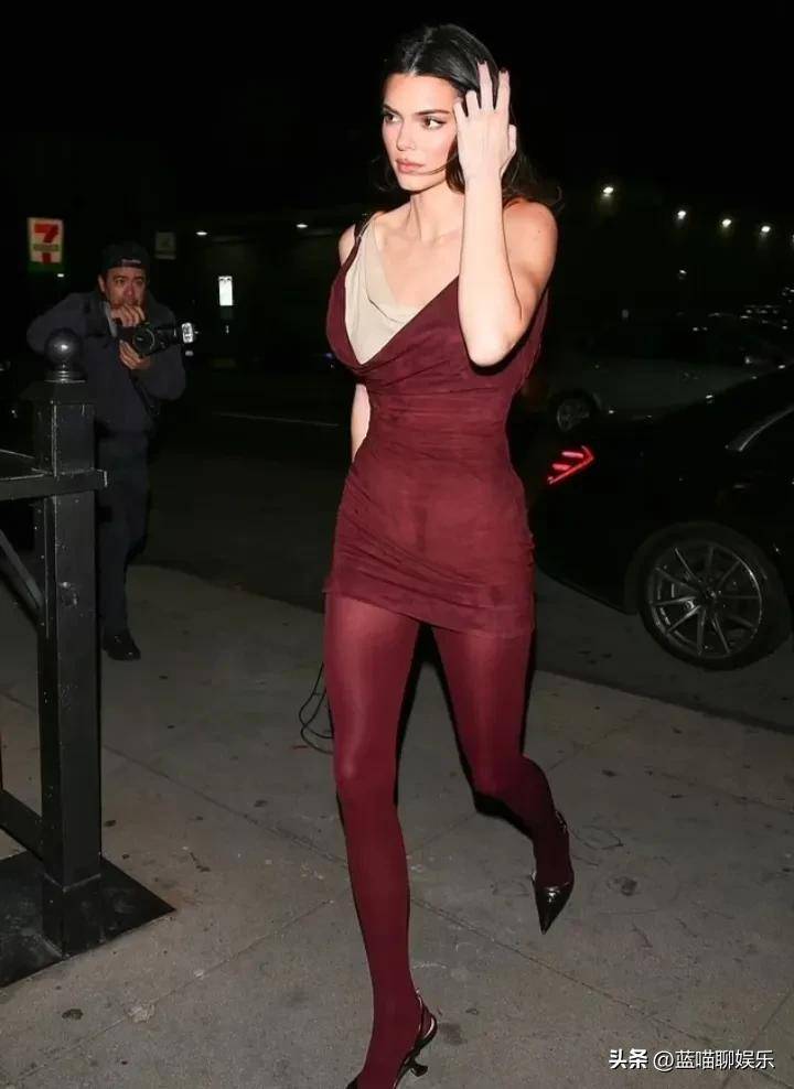 肯达尔·詹娜穿着酒红色迷你裙,搭配紧身丝袜,展示性感的大长腿