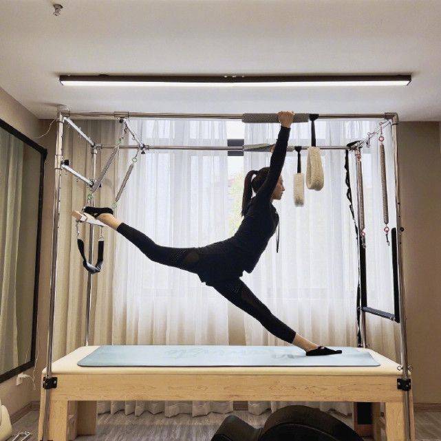 董璇双手握着两条杠,一条腿放在设备上,另一条腿踩在瑜伽垫上做一匹马