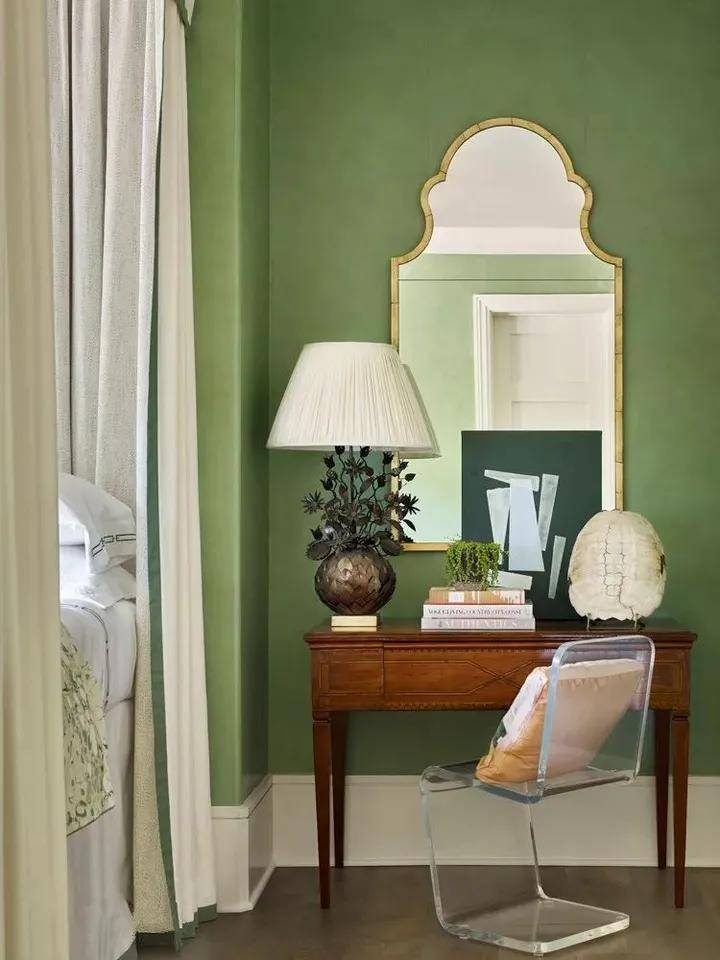 这间舒适的绿色和奶油色的卧室贴着仿威尼斯石膏外观的抹茶色墙纸