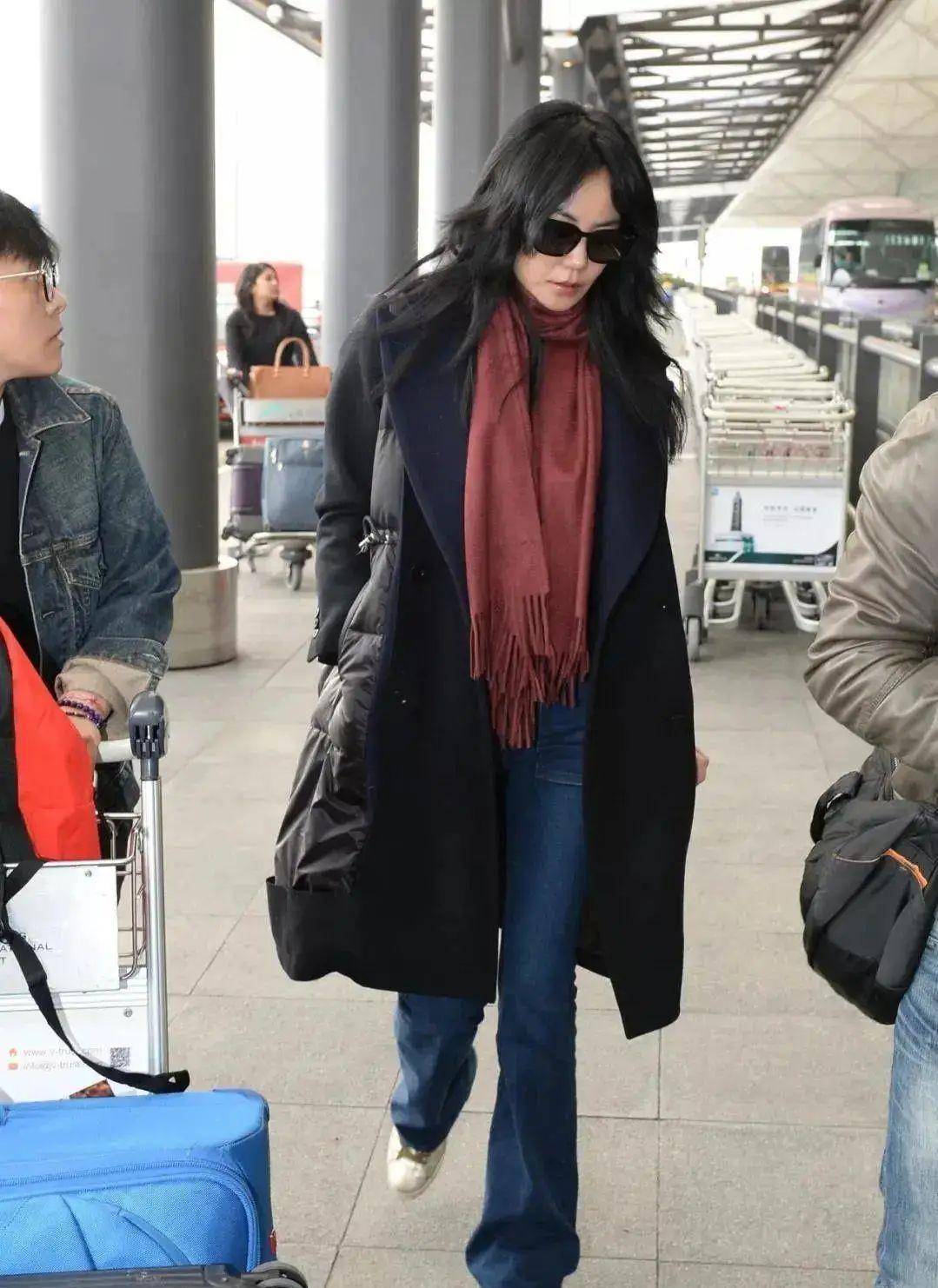在机场,王菲选择了一件拼接羽绒服搭配微喇叭牛仔裤和酒红色围巾.