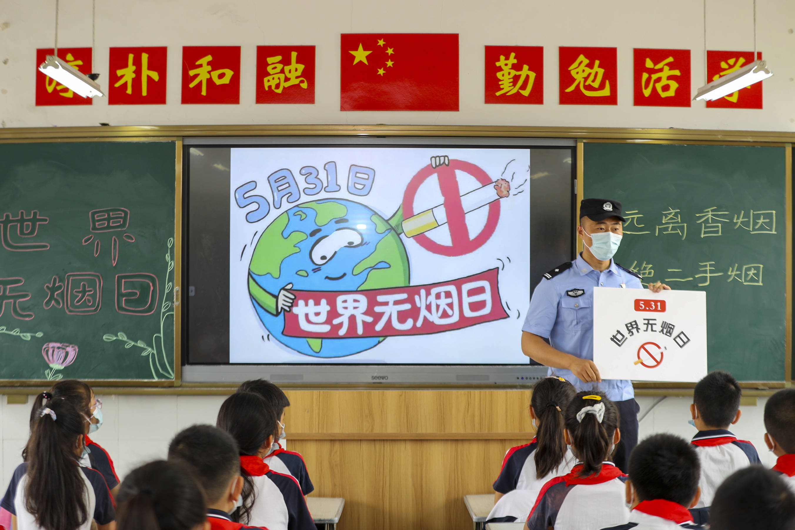 2022年5月30日,民警帮助泰州市九龙实验学校学生进行禁烟手抄报绘制.