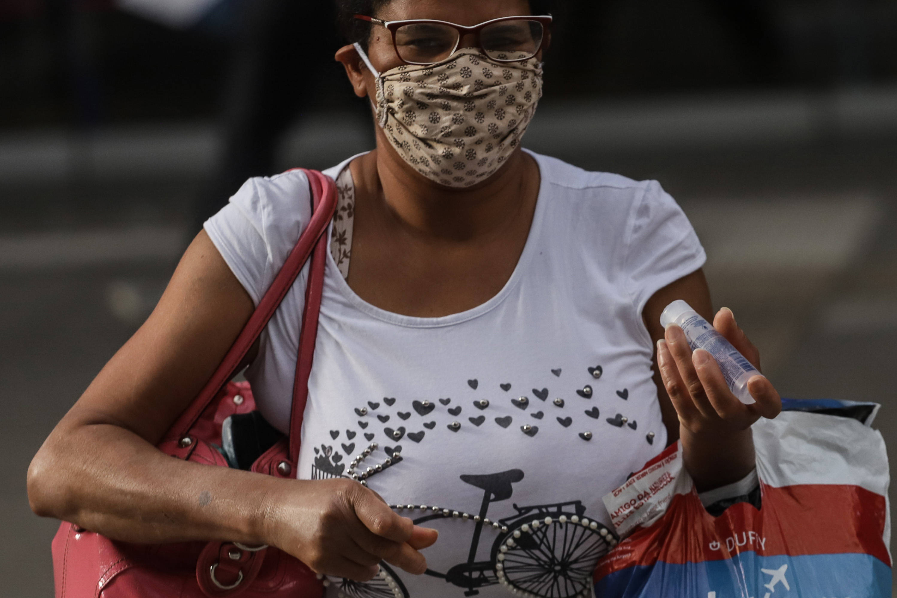 6月8日,一名戴口罩的女子手持酒精凝胶走在巴西圣保罗市街头