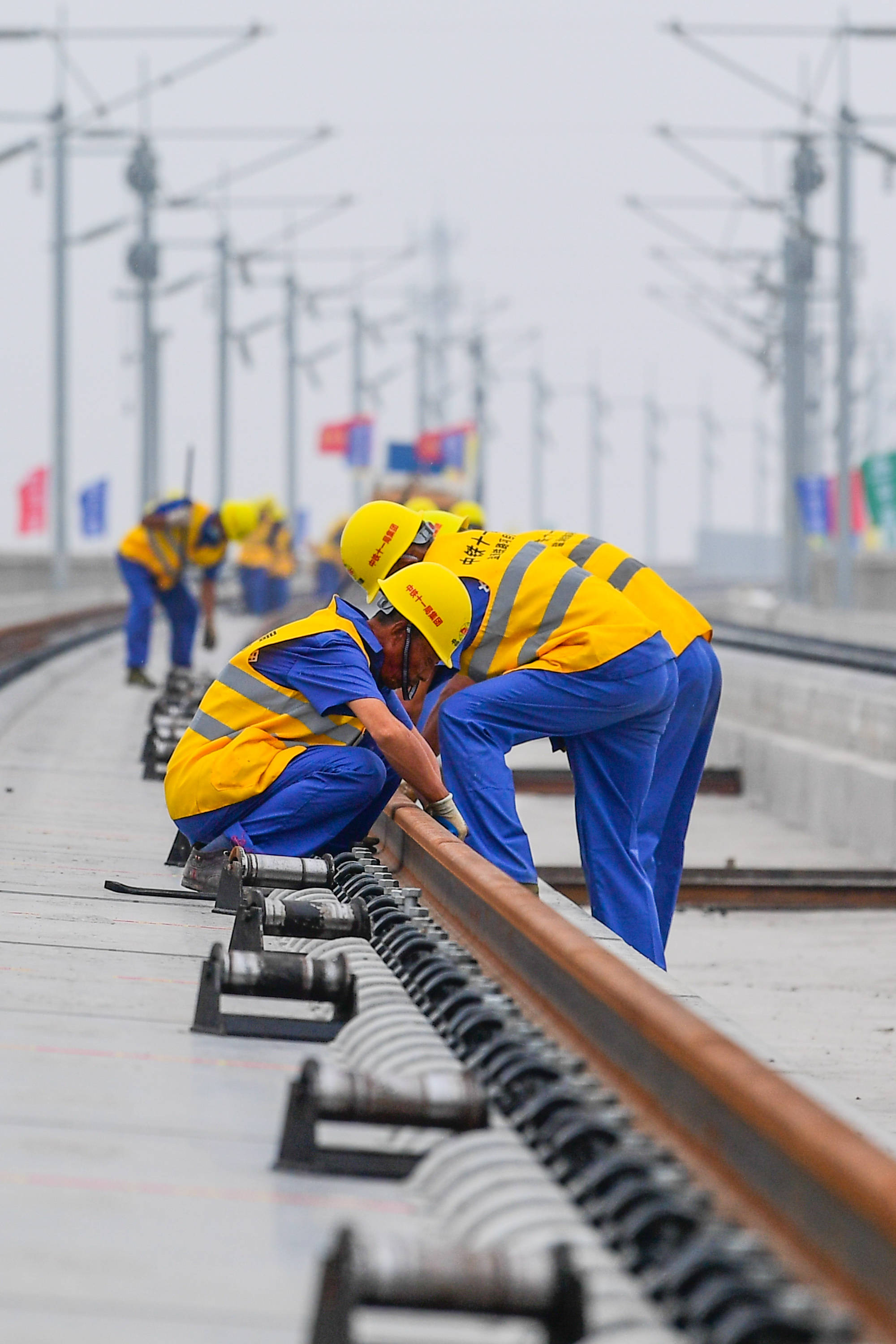 6月12日,中铁十一局的工程人员在安装轨道钢轨轨距挡块.