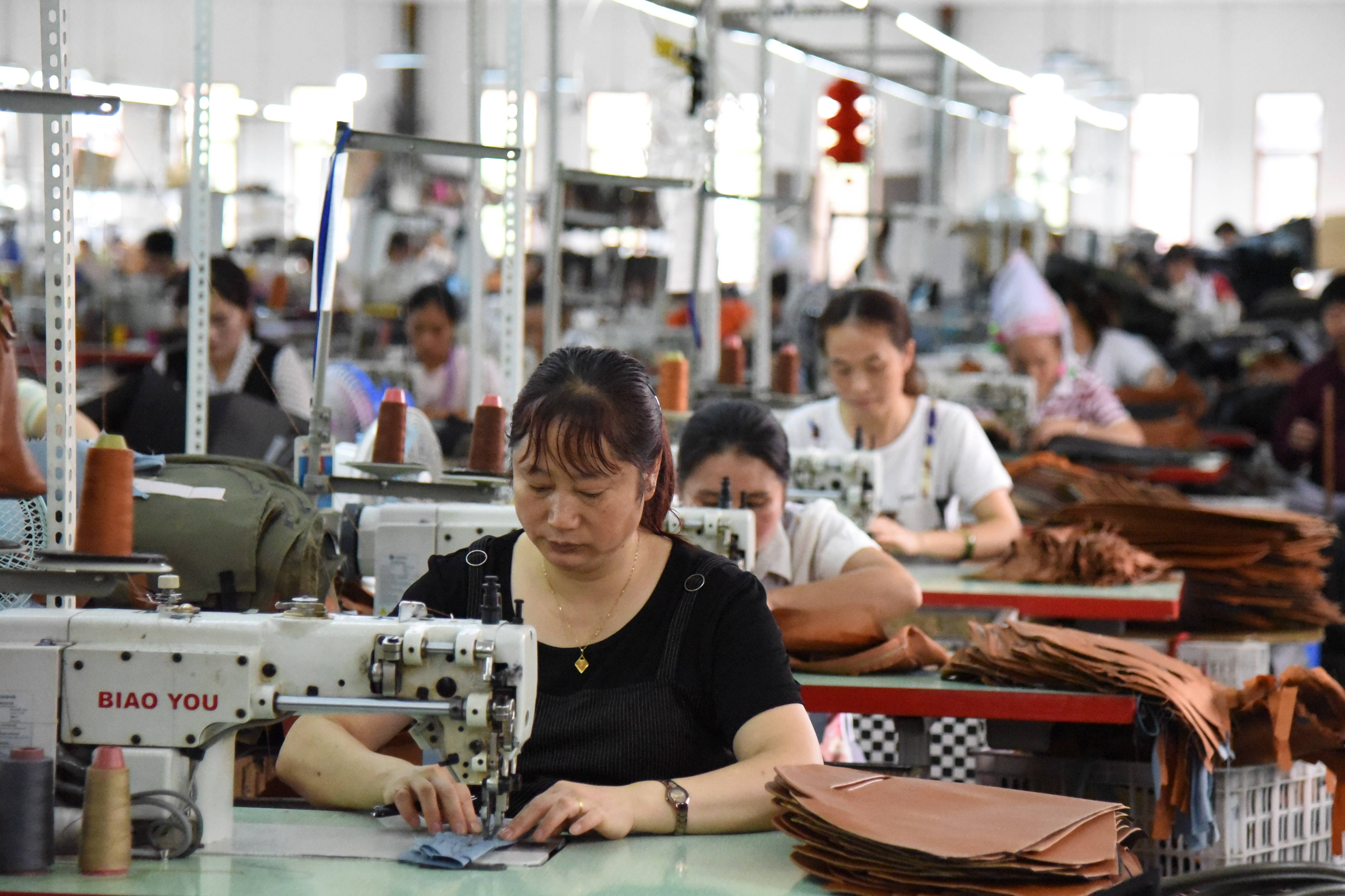 工人在贵州省普安县才华手袋实业有限公司生产车间工作(6月19日摄)