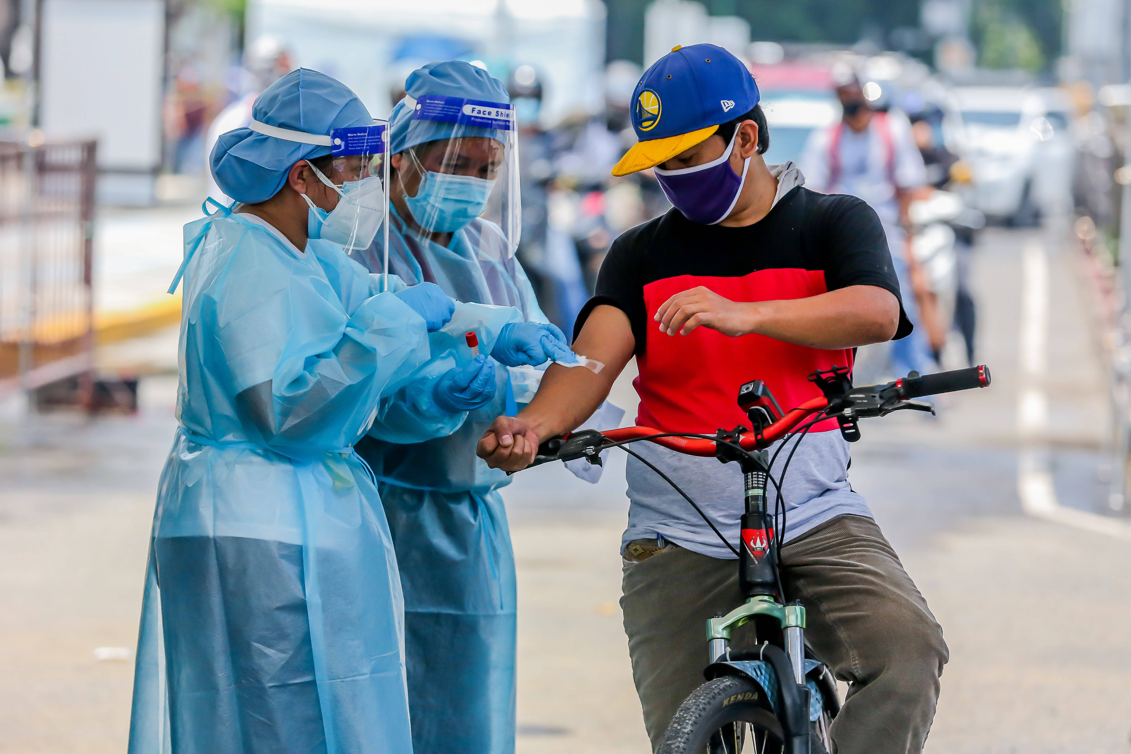 7月15日,医护人员在菲律宾首都马尼拉一处得来速式新冠病毒检测点