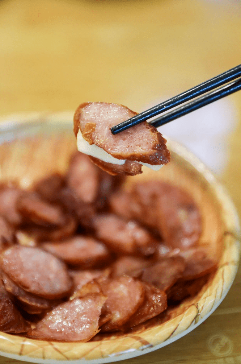 带你吃遍宁波提供 盘中放了奶白的蒜片,将它夹在台式香肠中,模样