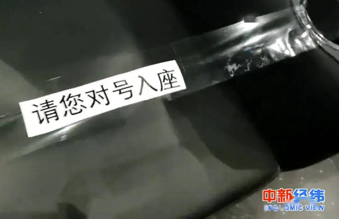 工作人员已用胶带将三个座位连在一起,胶带上提示"请您对号入座"