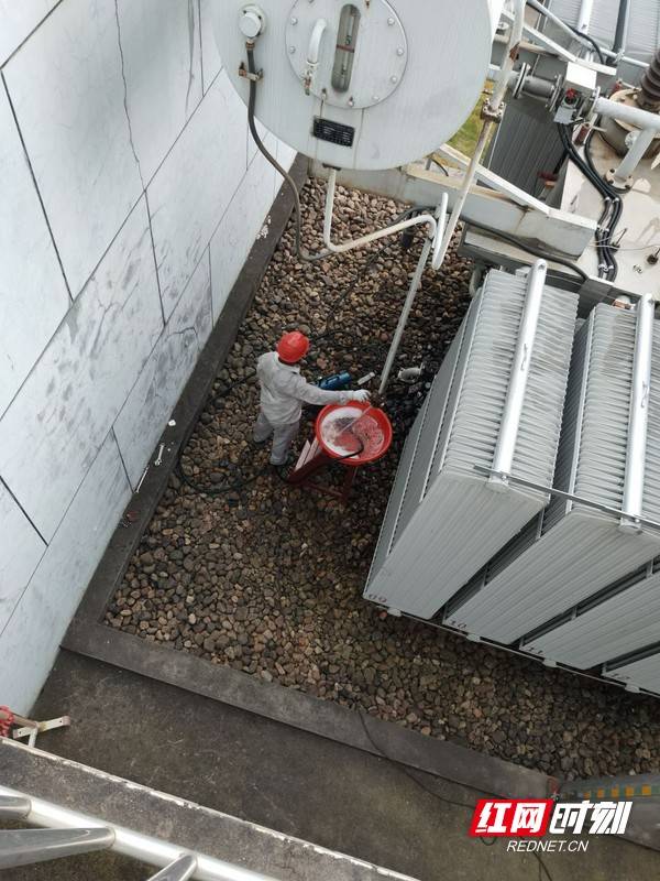 抢修人员对2号主变油枕进行排油,为消缺做准备.