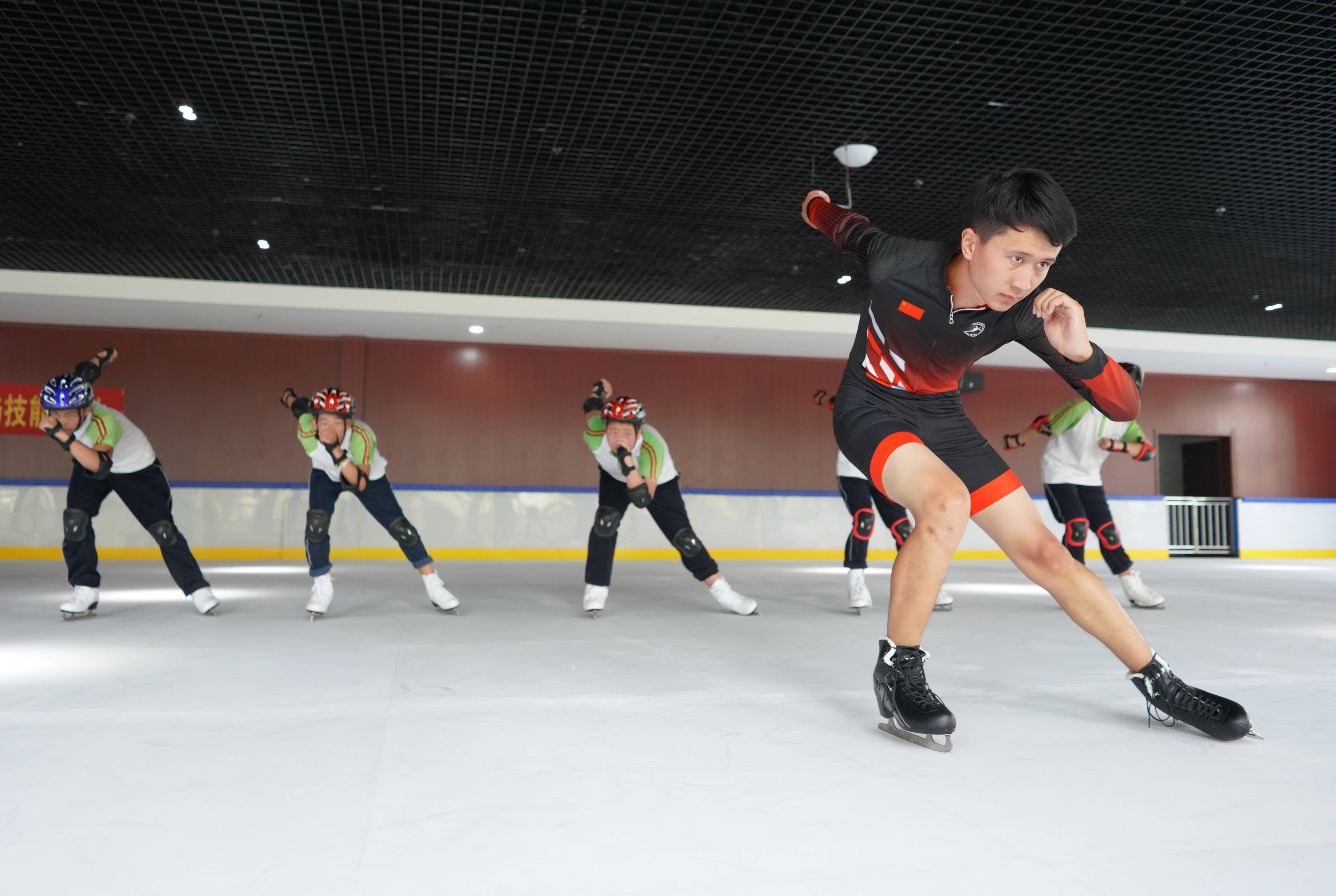 一名教练(前)带领学员们练习滑冰基本动作