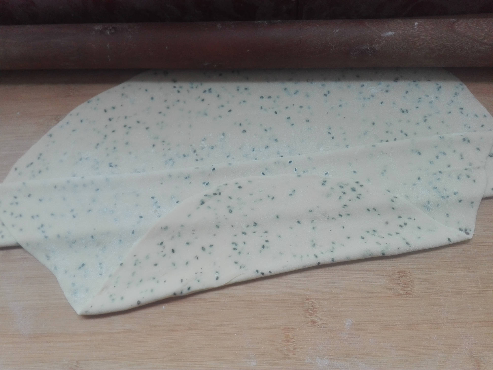 醒发两次的面团,取出放在案板上,将其用擀面杖擀成均匀厚度的薄面片