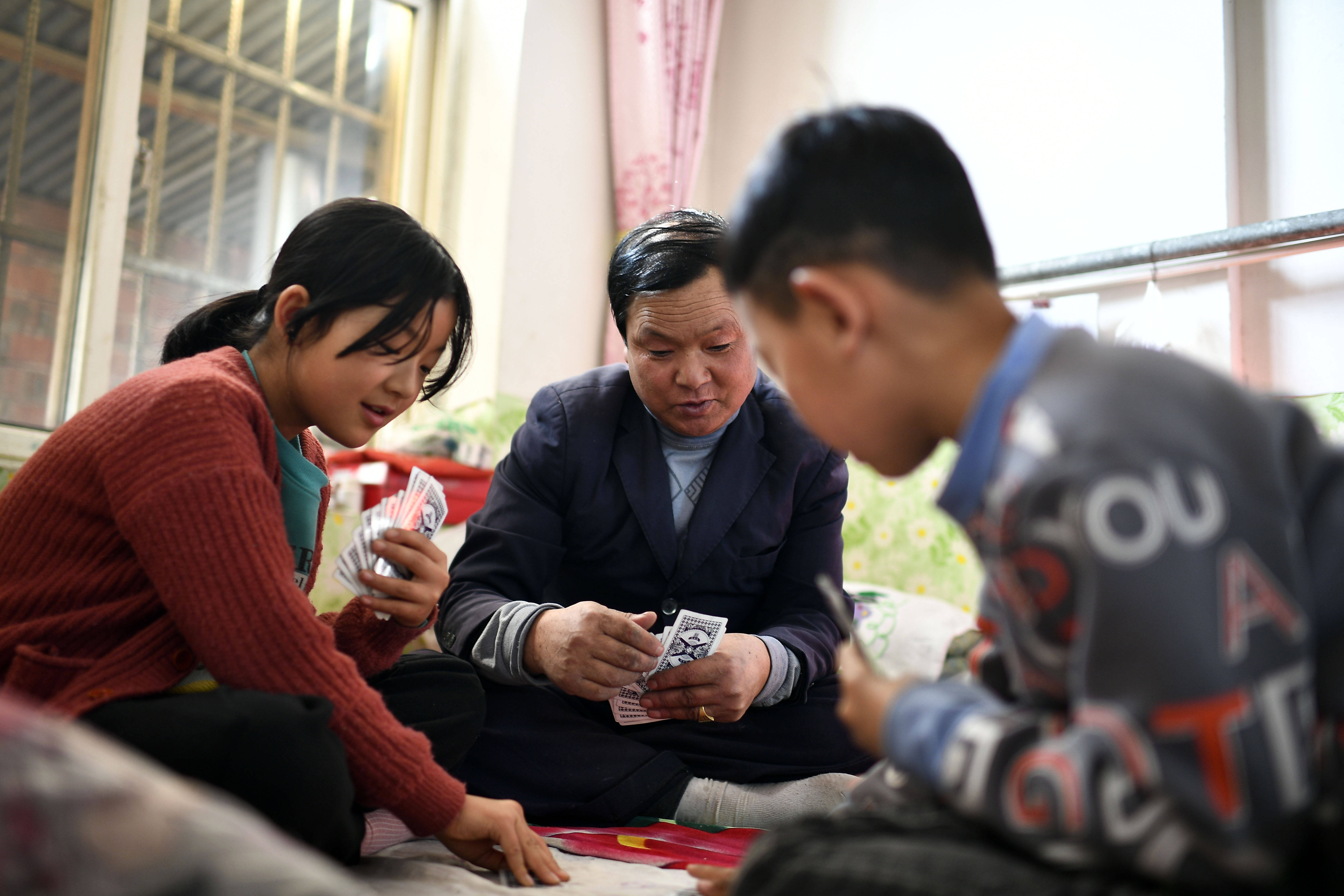 2月11日,张俊明在滨河家园移民村的家中与家人打扑克