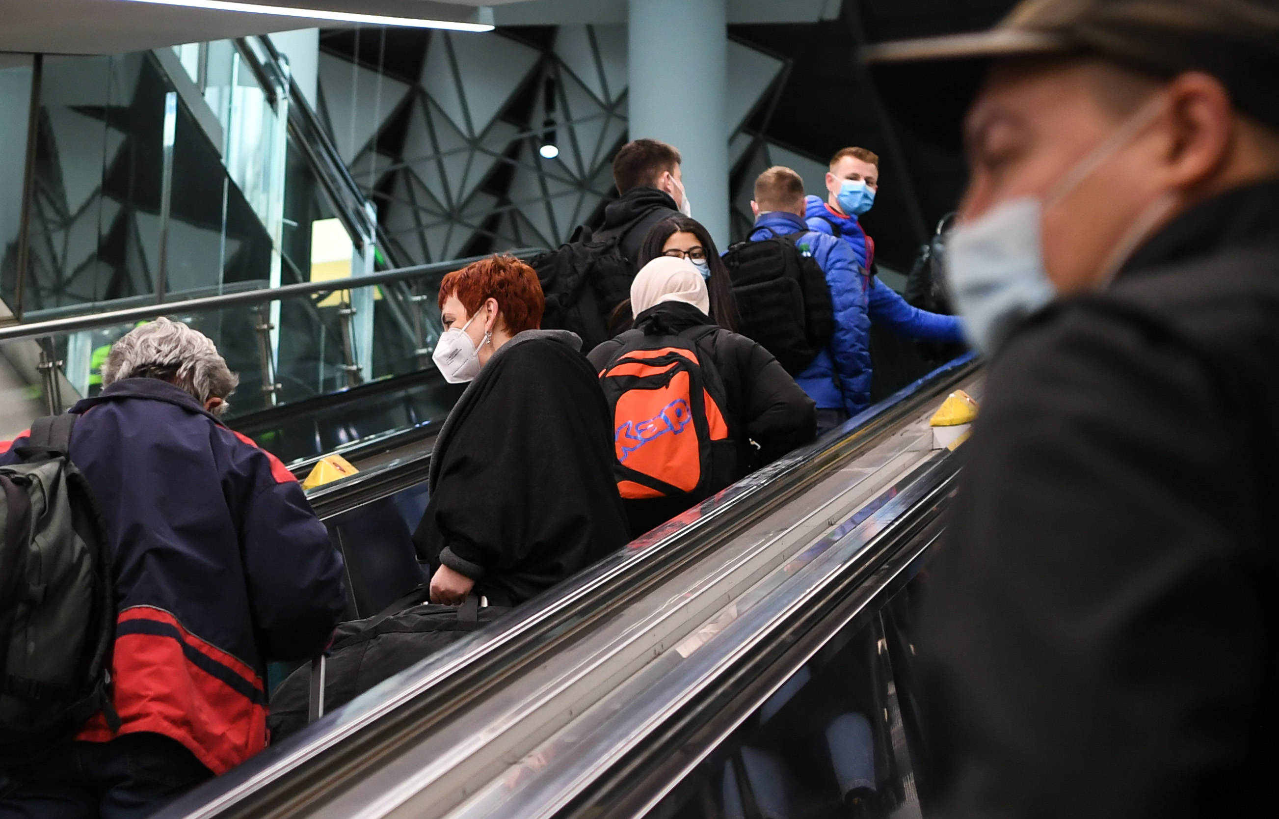 3月18日,在德国法兰克福机场,戴口罩的人们乘扶梯上行.