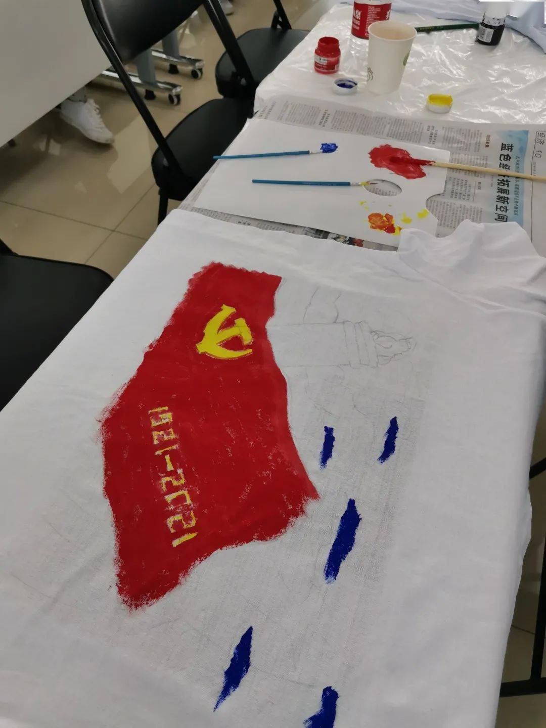 青年们自己动手制作"文化衫",在文化衫绘制出党旗,和平鸽,建党100周年