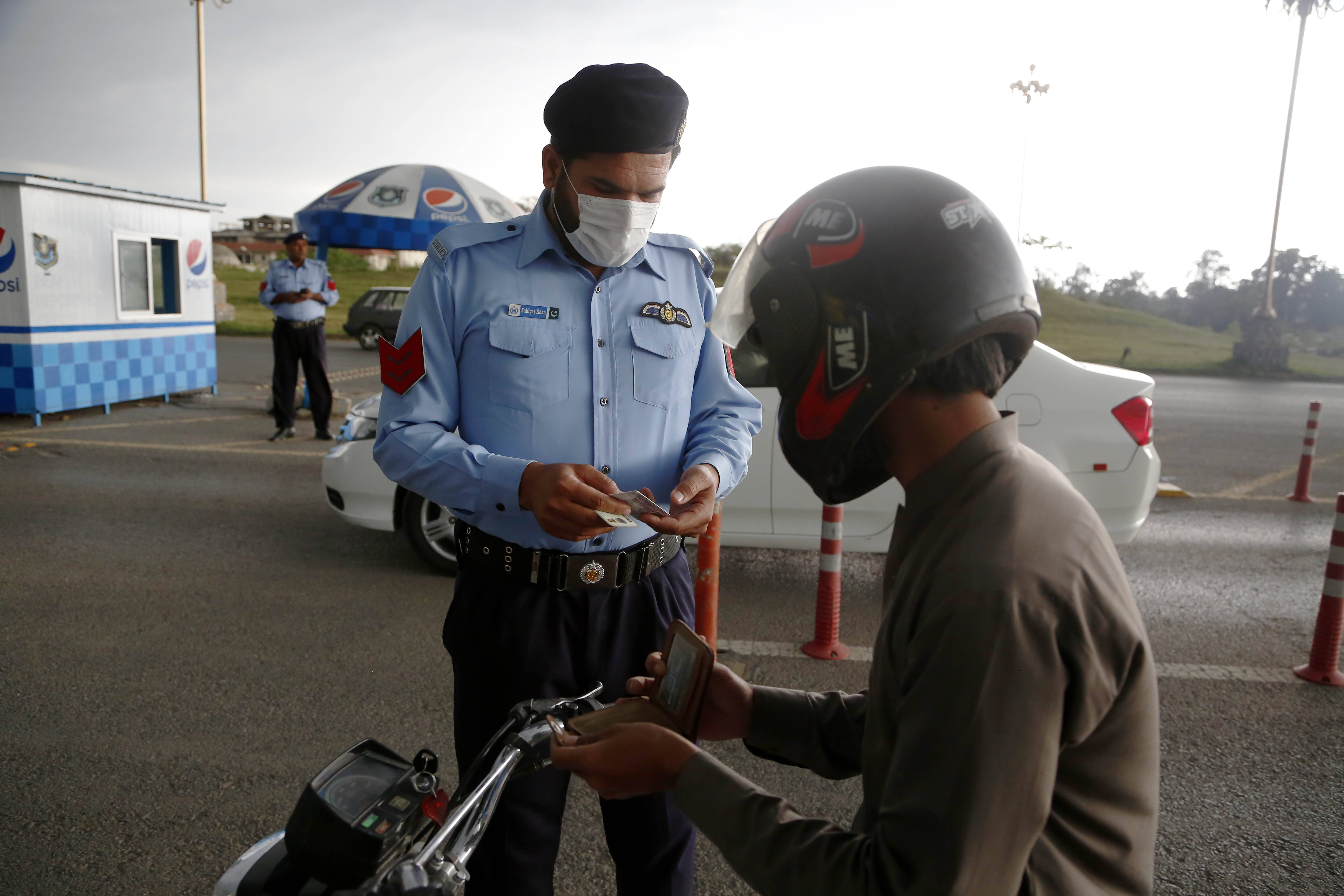 4月22日,警察在巴基斯坦伊斯兰堡一处检查点查看摩托车驾驶员证件