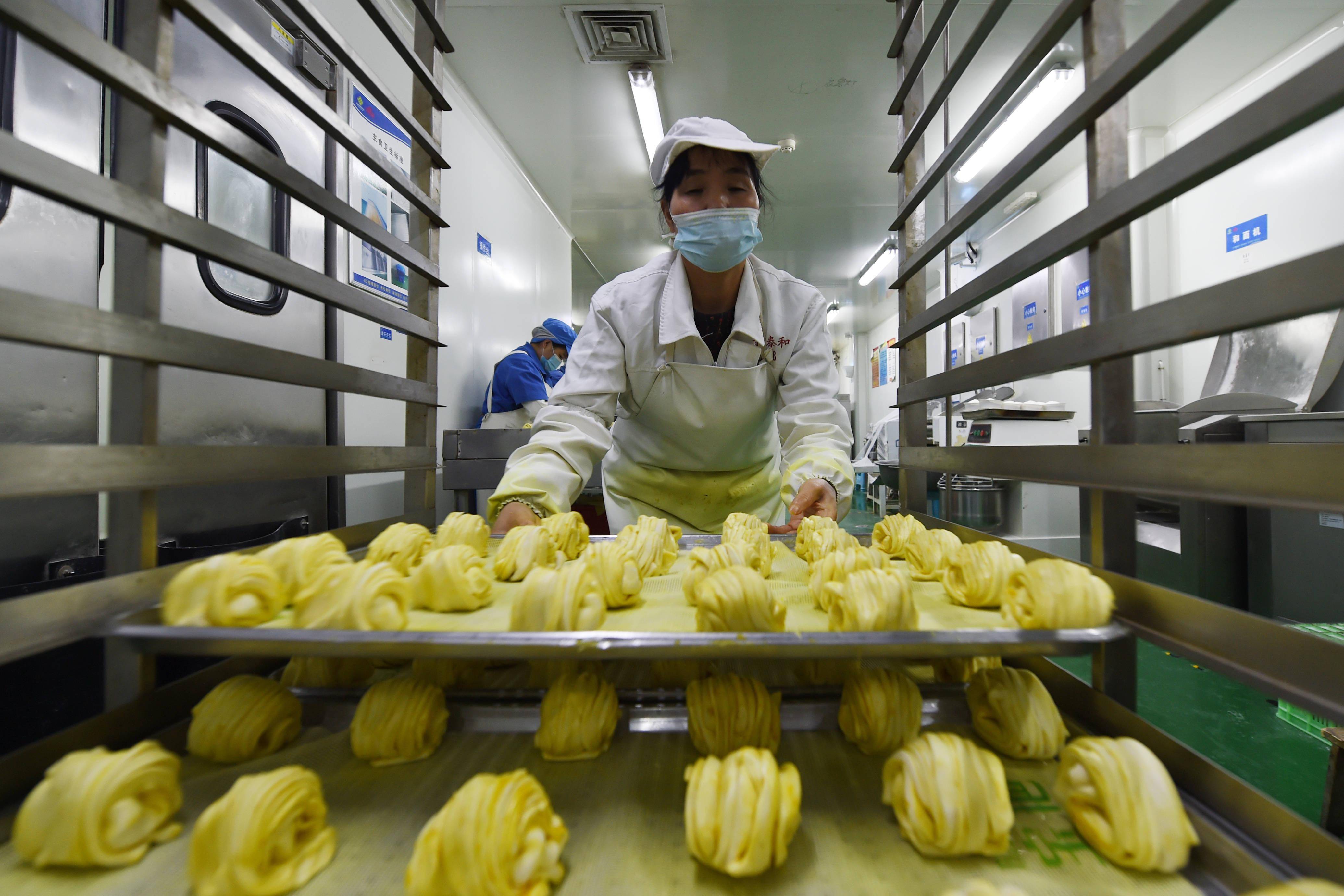 10月26日,在兰州市安宁区一家餐饮集团的中央厨房,工作人员在制作花卷