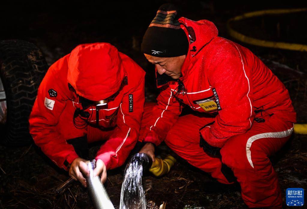 在长白山国际度假区,孙德胜(右)与同事在雪道上检修造雪机器(11月19日