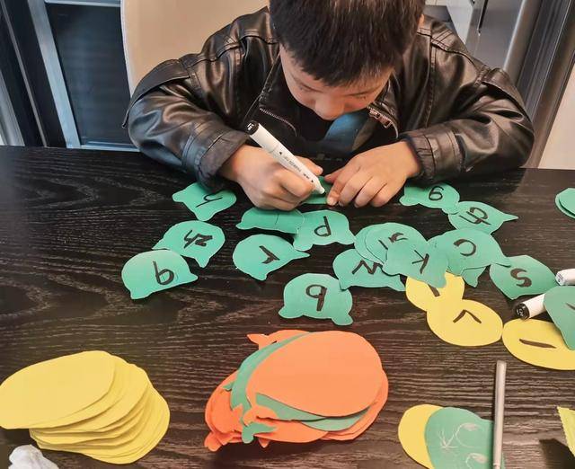 孩子们将纸张剪成了形状各异的拼音卡片.并在卡片上书写字母.