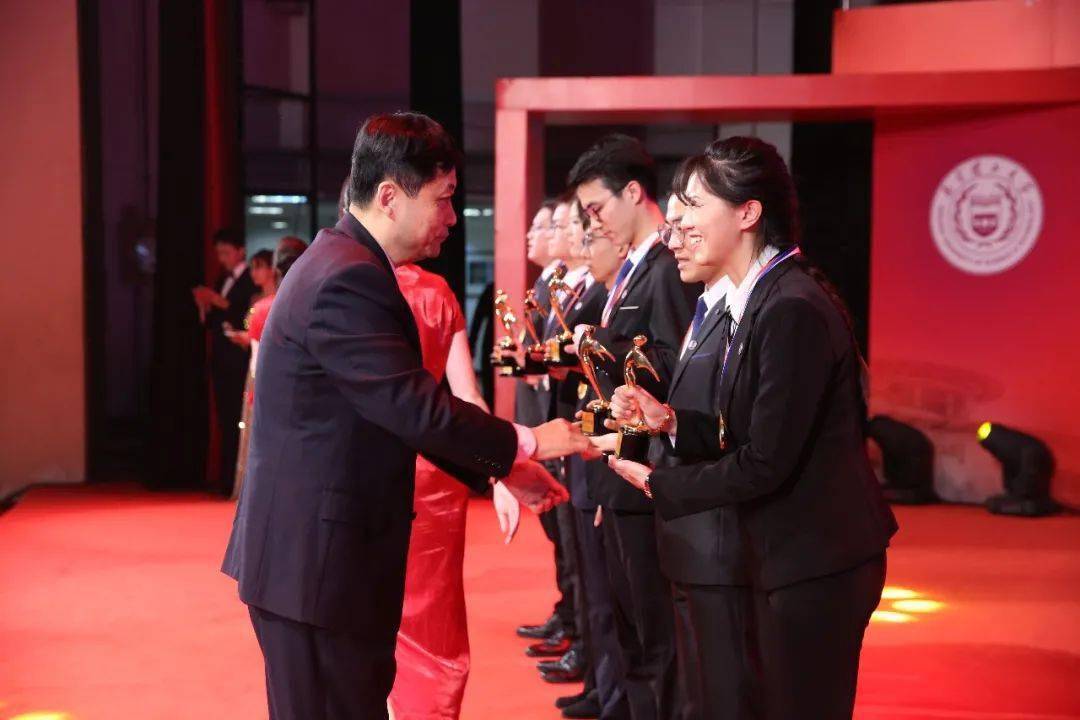 校党委书记张骏为获得 "青年五四奖章"的学生颁发奖杯并佩戴奖章.