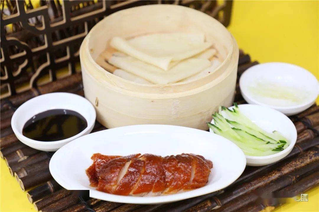 京葱丝蘸上甜面酱薄饼皮包裹着新出炉的脆皮鸭肉挑出最精华的部分装盘