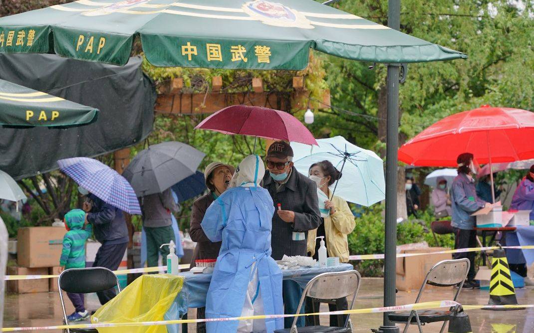 多图｜北京朝阳区临时管控区居民雨中做核酸，自觉保持“一米线”