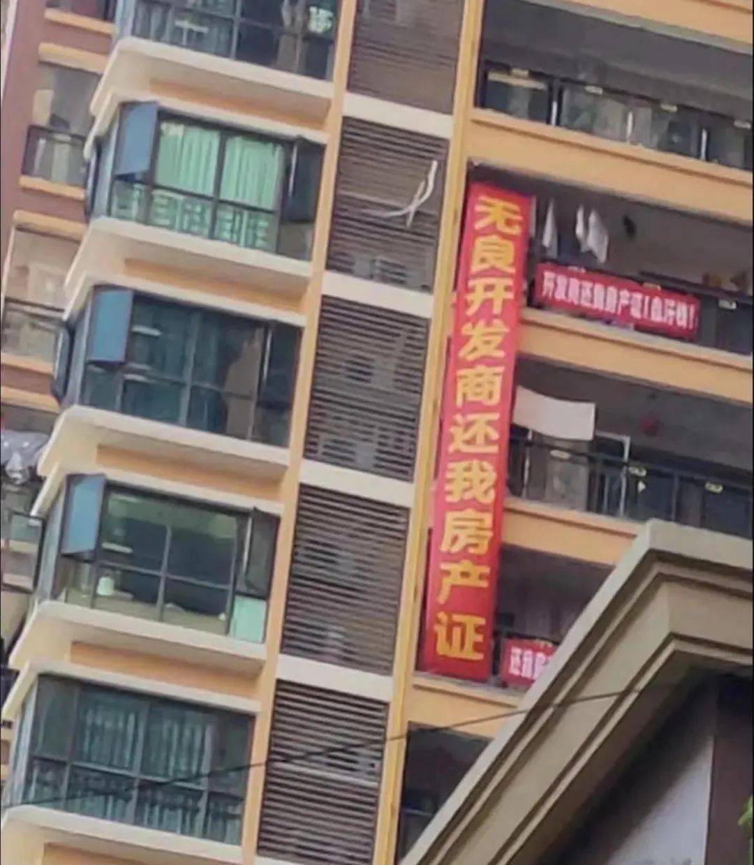 外边挂上印有"无良开发商还我房产证"黑心楼盘欺骗业主"字眼的横幅